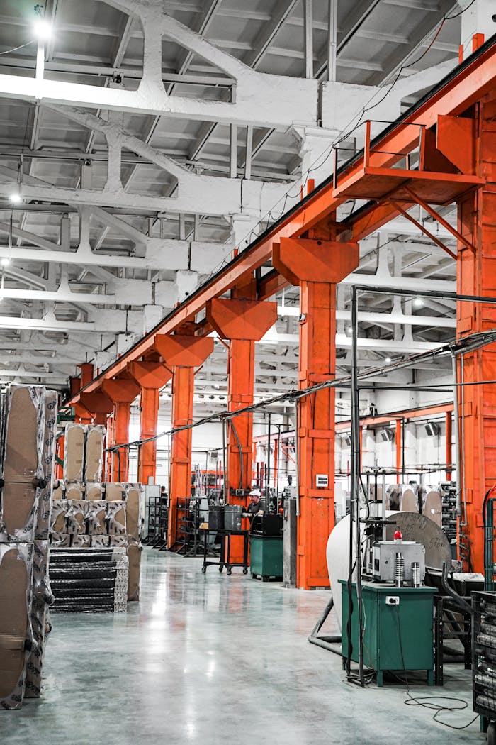 Services Spacious industrial factory hall with vibrant orange pillars and machinery, ideal for production themes.